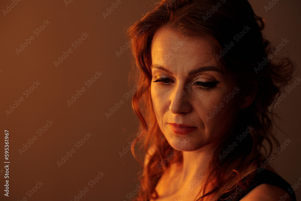Stressed sad mature woman looking down thinking about her problems Stressed sad mature woman looking down thinking about her problems