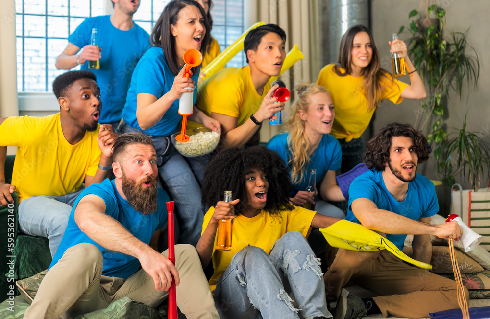 Obraz premium Soccer fan supporter friends cheering and watching football cup match at home Intenational - Group young people with multicolor t-shirts having fun with sport world championship concept