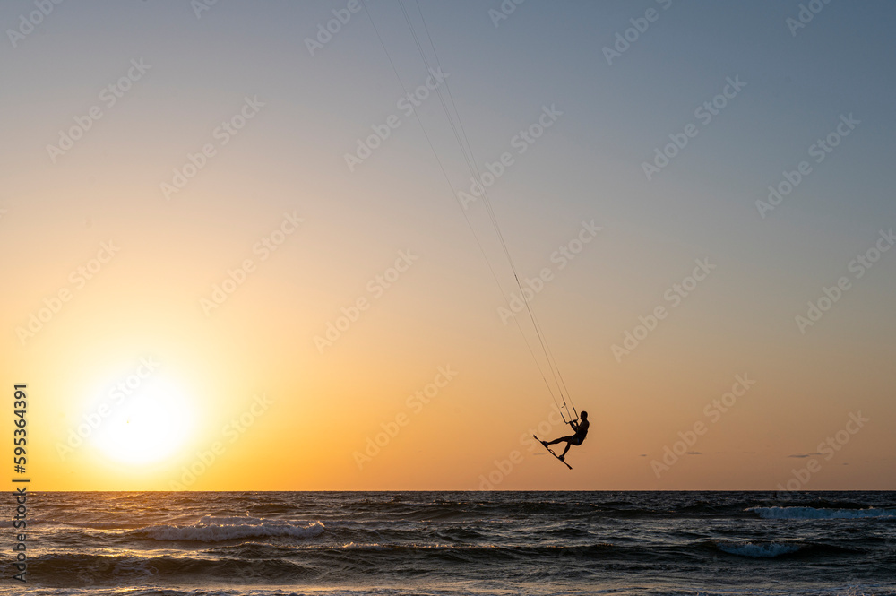Black silhouette of a man on a wakeboard taking off over the