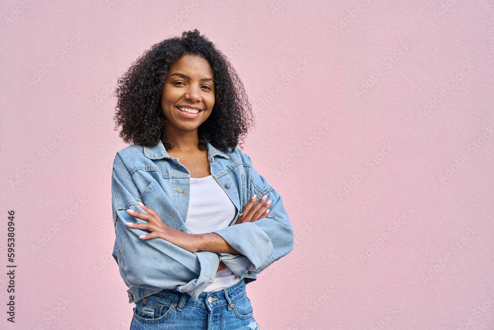 © Stock 4 You - Young stylish woman model pose in denim jacket in front of soft pink background looking at camera. Beautiful curly hair african american girl in trendy clothes with crossed arms smile with copy space. © Stock 4 You - Young stylish woman model pose in denim jacket in front of soft pink background looking at camera. Beautiful curly hair african american girl in trendy clothes with crossed arms smile with copy space.