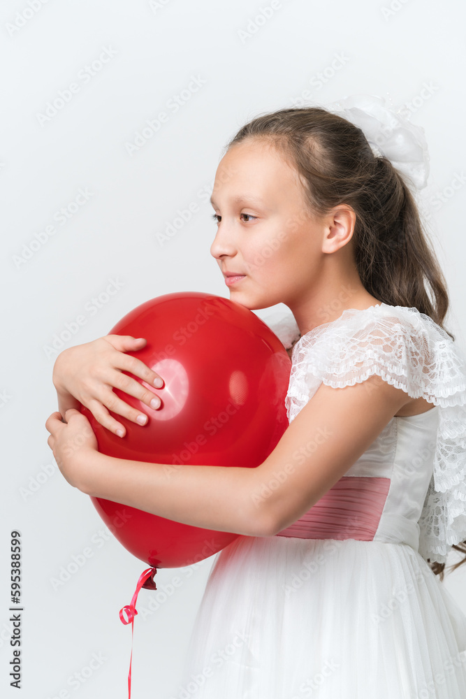Portrait of girl hugging red balloon with both hands, put chin on ball, looking to side. Beautiful model of ten years old in white dress. Studio shot of girl on white background. Part of photo series. Portrait of girl hugging red balloon with both hands, put chin on ball, looking to side. Beautiful model of ten years old in white dress. Studio shot of girl on white background. Part of photo series.