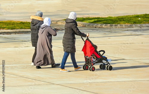 muslim women walking through park carrying baby in carriage