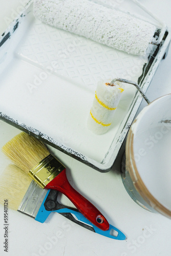 A builder in a white work uniform pours paint into a container, construction tools, spatula, brush close-up