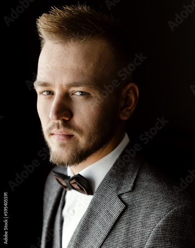 a young and handsome groom in a suit and a vest with a bow tie is assembled for the wedding. successful entrepreneur marries. successful man. portrait of the groom