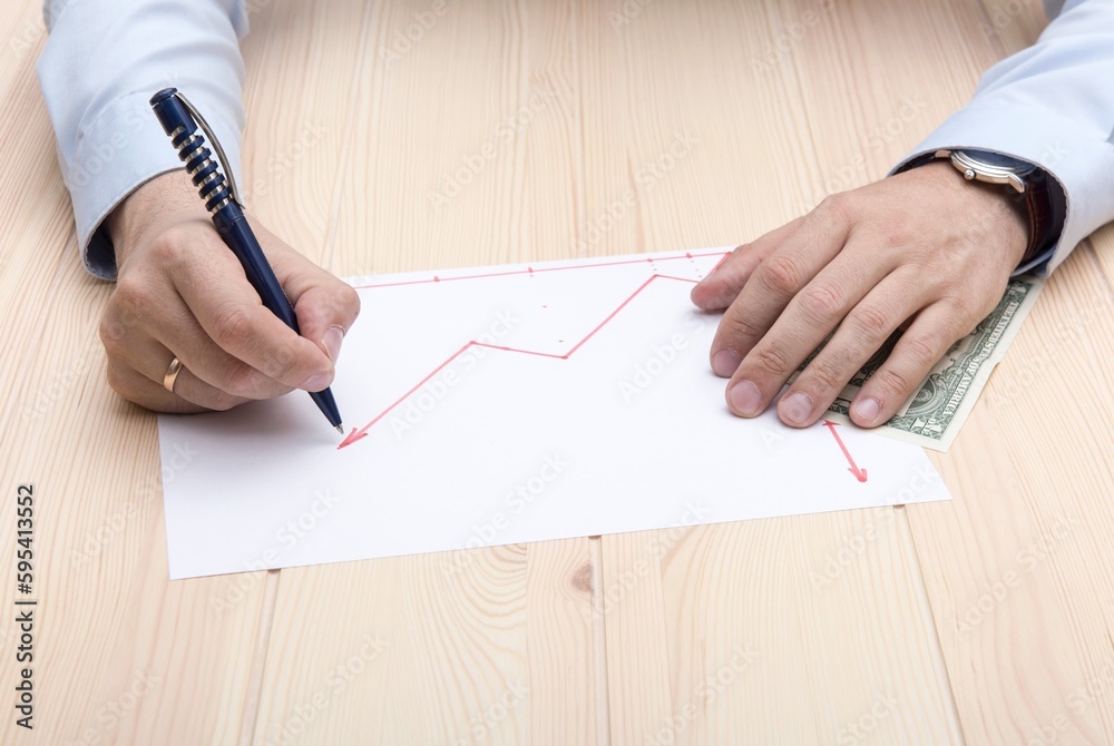Close-up of a man's hands, with a ring on his hands, draw a graph of the growth of stock prices on a piece of paper. Close-up of a man's hands, with a ring on his hands, draw a graph of the growth of stock prices on a piece of paper.