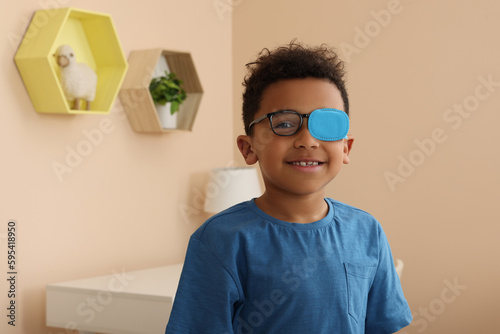 Fotografija African American boy with eye patch on glasses in room, space for text