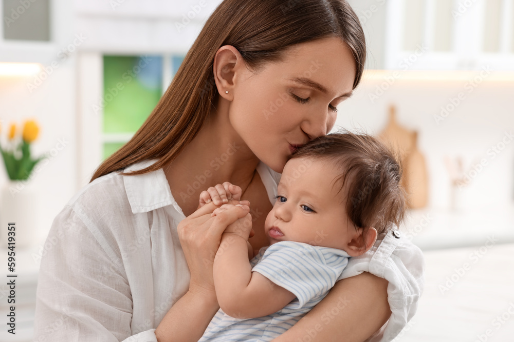 Happy mother kissing her little baby in kitchen Happy mother kissing her little baby in kitchen