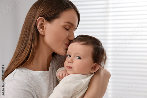 Happy mother kissing her little baby indoors