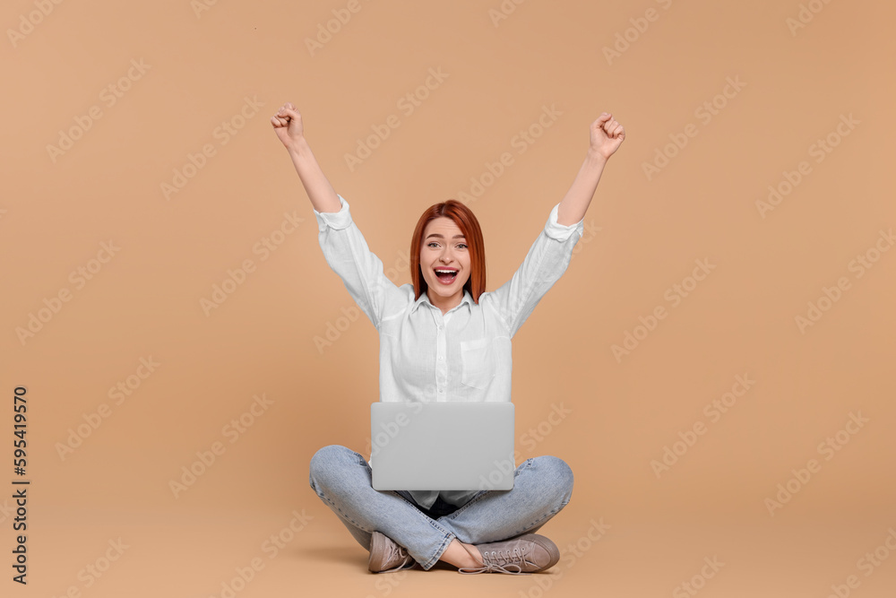 Happy young woman with laptop on beige background