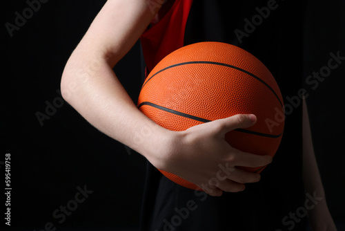 Boy with basketball ball on black background, closeup