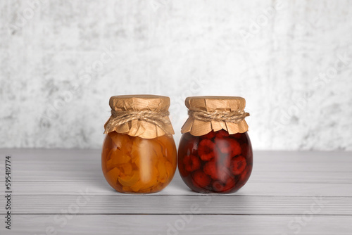 Jars with canned fruit jams on wooden table