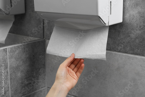 Obraz na płótnie Woman taking new fresh paper towel from dispenser in bathroom, closeup