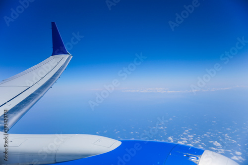 aerial view from a window seat captures the majestic airplane wing soaring through the clouds  symbolizing freedom  adventure  and travel. The view offers a sense of perspective