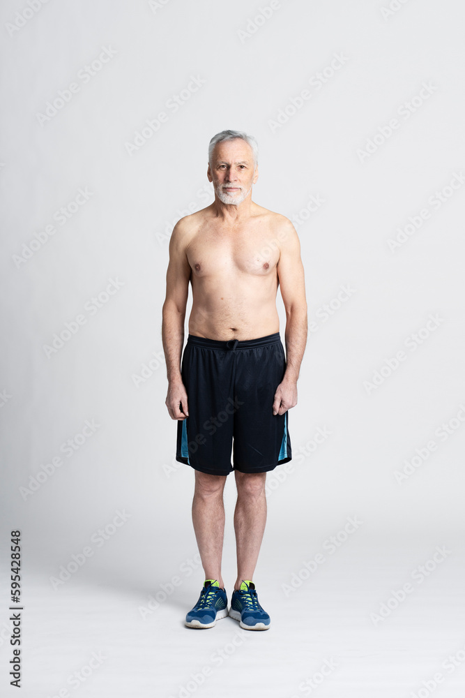 Handsome senior man standing isolated on white background with naked torso, looking at camera