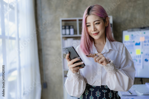 Asian woman talking on the phone, looking at the screen. Young accountant consulting clients on the phone, financial adviser concept.