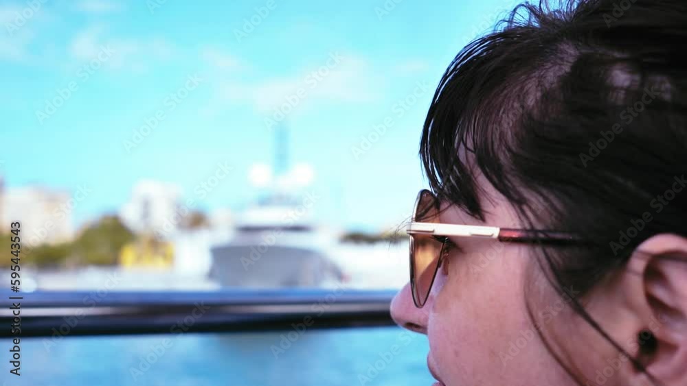 Traveler enjoying a boat ride: Woman in sunglasses exploring the scenery from the deck in close-up Traveler enjoying a boat ride: Woman in sunglasses exploring the scenery from the deck in close-up
