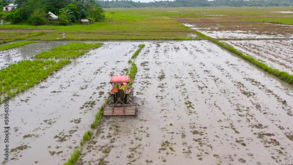 Paddy field with water, top view. Agriculture in the Philippines. Tractor is plowing, preparing the soil for rice cultivation, to make the soil friable, suitable for rice cultivation. Paddy field with water, top view. Agriculture in the Philippines. Tractor is plowing, preparing the soil for rice cultivation, to make the soil friable, suitable for rice cultivation.