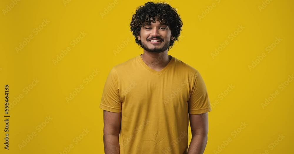 Young indian man satisfied happy guy standing over yellow background Young indian man satisfied happy guy standing over yellow background