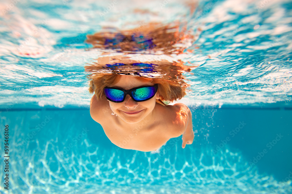 Fototapeta premium Child in swimming in pool. Funny little boy swims underwater in the pool. Underwater kids portrait from under the water. Summer holiday. Kids weekend.