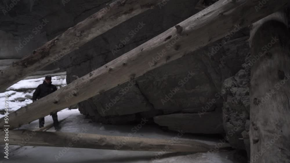 man walking through maligne canyon among logs on frozen river in slow motion man walking through maligne canyon among logs on frozen river in slow motion