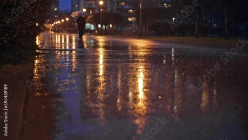 Person Walking with Umbrella Through City Park Empty Boulevard on Rainy Evening