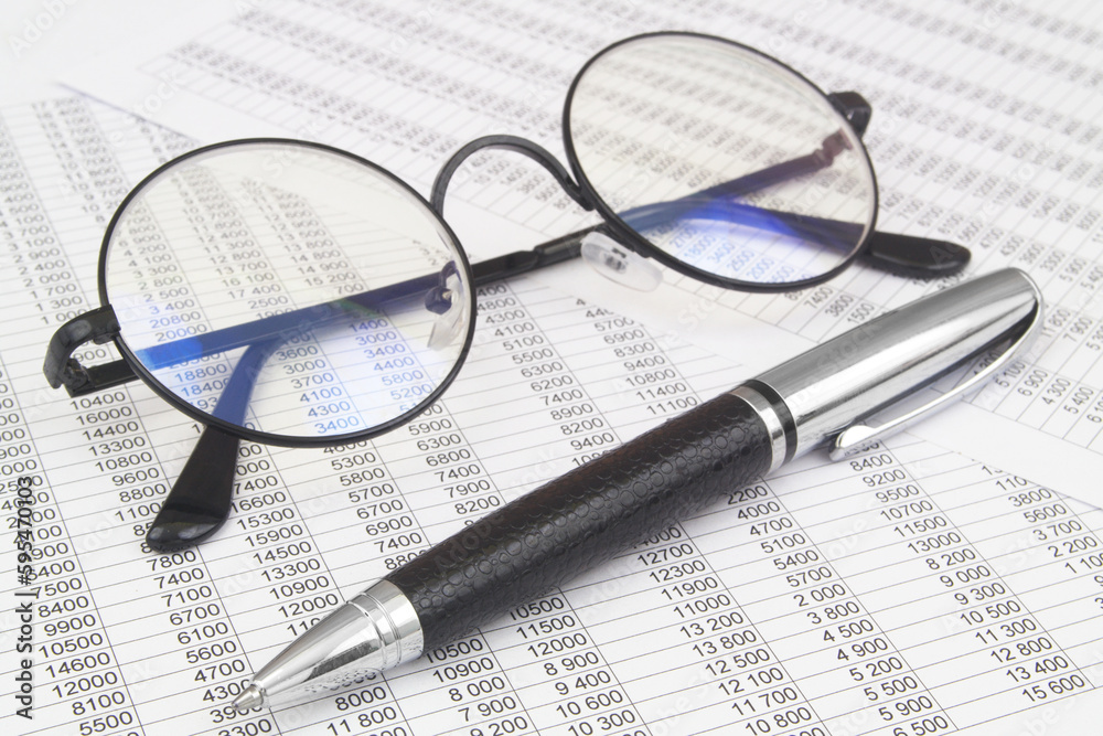 Eyeglasses and pen on financial documents with many numbers. Business and accountancy concept. Eyeglasses and pen on financial documents with many numbers. Business and accountancy concept.
