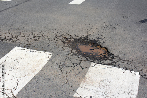 Pot Hole near pedestrian crossing in suburban street, hole in road