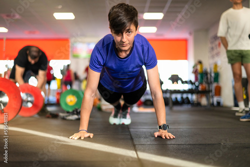 Young Athlete Woman Trained In The Gym To Strengthen Bodybuilding  Is In Plank Position.