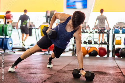 Fit And Muscular Woman Focused On Lifting A Dumbbell During An Exercise Class In A Gym.