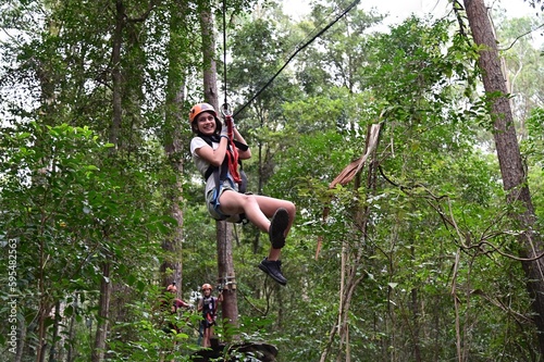 Teenager girl sliding on a flying fox zip line during a treetop adventure climbing