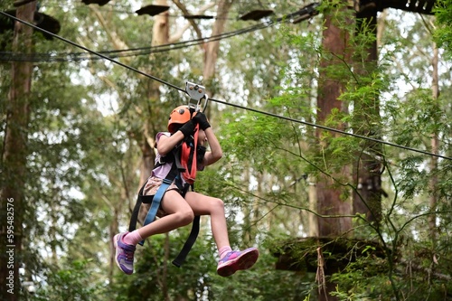 Obraz na płótnie Young girl sliding on a flying fox zip line during a treetop adventure climbing w salonie