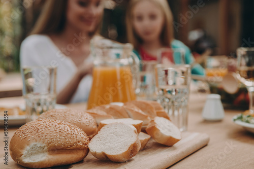 Close-up of freshly baked bread laying on the table with family dining in the background