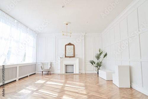 Bright interior with large windows and a fireplace in a classic style. Large living room with decor items. Beautiful parquet and copy space. Sunlight and shadows in the room. High quality photo