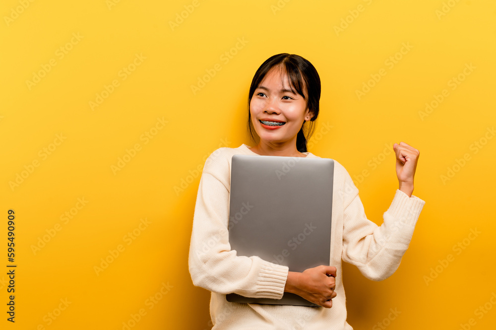 Asian woman and laptop and are happy to work Photo of a beautiful Asian woman who is happy working at home. using a laptop computer yellow studio work at home concept Asian woman and laptop and are happy to work Photo of a beautiful Asian woman who is happy working at home. using a laptop computer yellow studio work at home concept