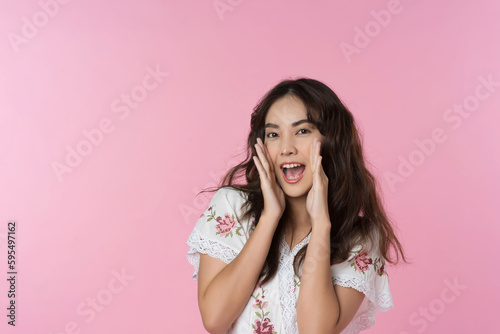 Young Asian woman doing a shocked surprise gesture shouting with hands cupped around mouth isolated pink color background