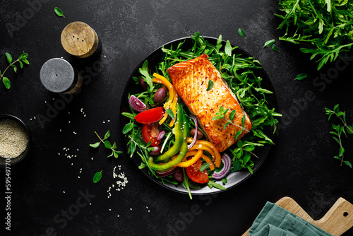 Tela Salmon fillet grilled and fresh vegetable green salad of arugula with tomatoes,