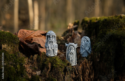 vintage ritual stone idols on tree stump close up, abstract natural forest background. old gods totems in traditional Slavic folk style. folklore Ethnic handicraft. Attribute of pagan religious rites. photo