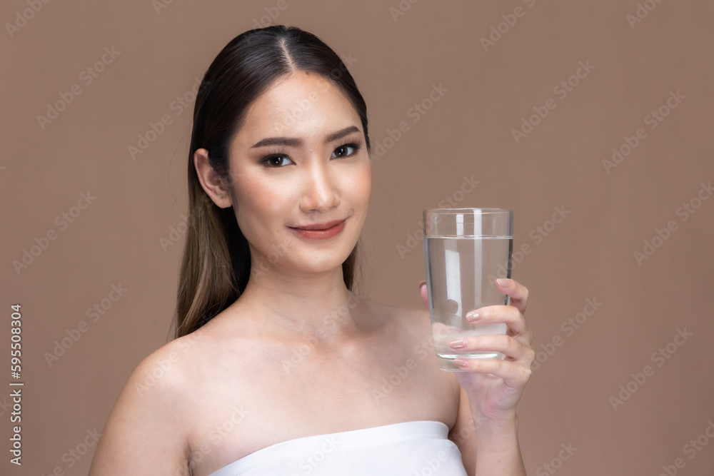 Young Asian woman holding glass of water on beige cream background.Beauty portrait of charm lifestyle healthy and beauty woman. Young Asian woman holding glass of water on beige cream background.Beauty portrait of charm lifestyle healthy and beauty woman.