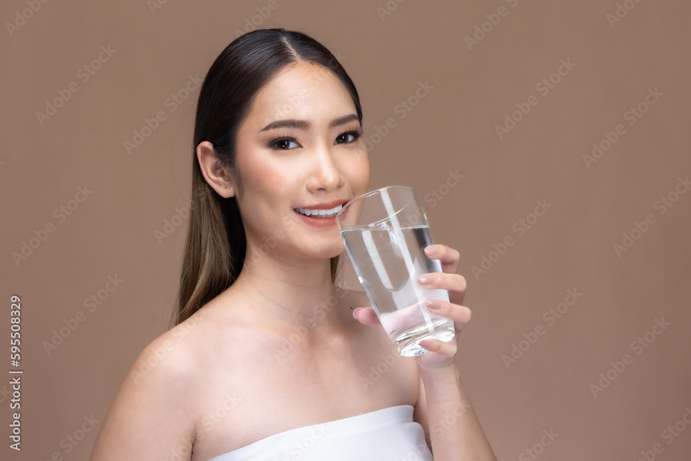 Young Asian woman holding glass of water on beige cream background.Beauty portrait of charm lifestyle healthy and beauty woman. Young Asian woman holding glass of water on beige cream background.Beauty portrait of charm lifestyle healthy and beauty woman.