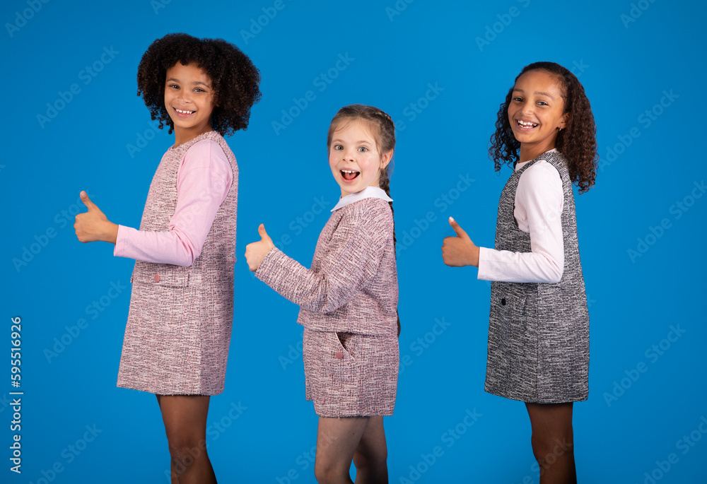 Glad shocked teen african american and european girls have fun, enjoy free time together, show thumbs up Glad shocked teen african american and european girls have fun, enjoy free time together, show thumbs up