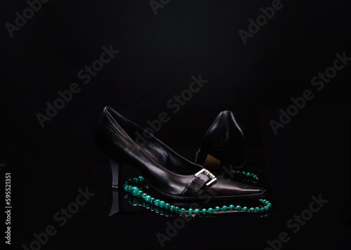 Art photo - necklace with modej shoes on dark background