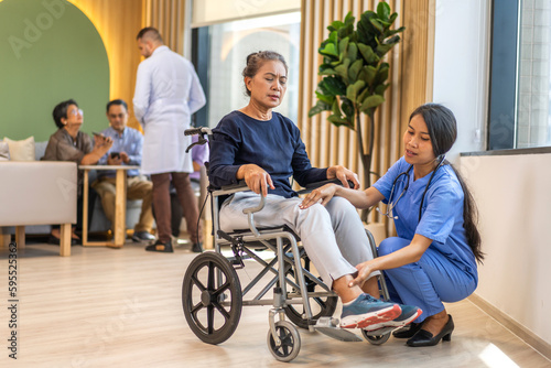 Portrait of asian woman physiotherapist carer helping physical and discussing consulting talk with senior woman patient by doing exercises sitting in wheelchair in rehabilitation at hospital