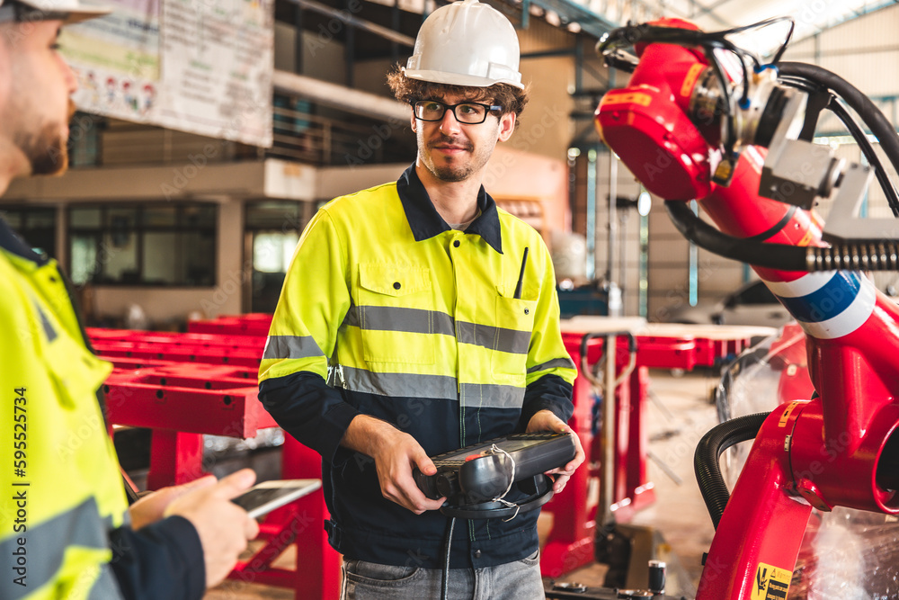 Fototapeta premium Factory worker with safety uniform discussion about robot arm working in factory workplace.