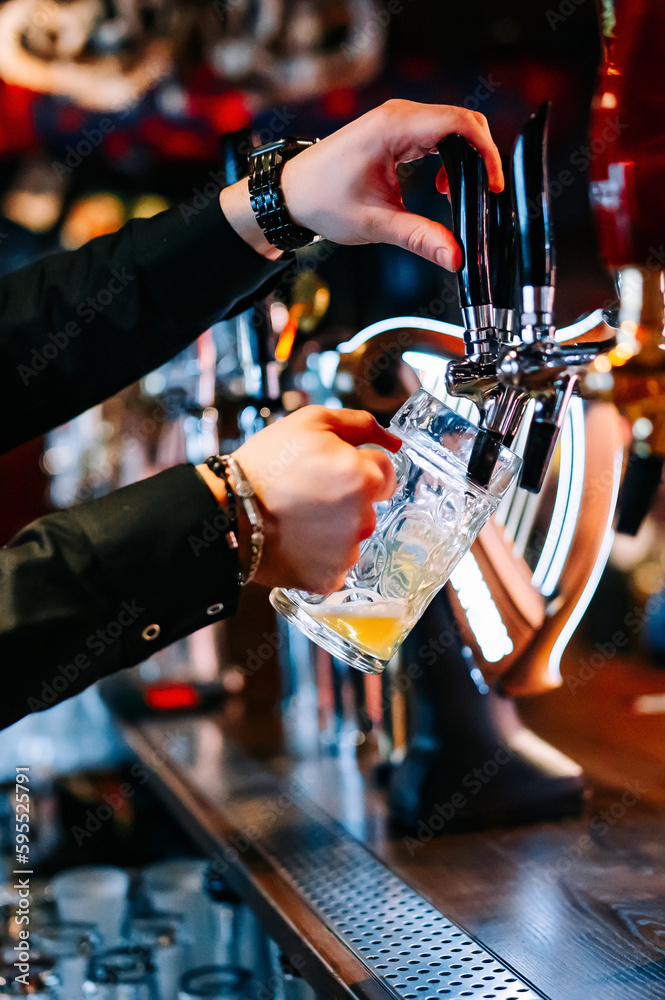 man bartender hand at beer tap pouring beer in glass in bar or pub