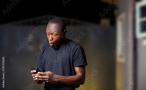surprised black man holding and using phone