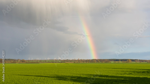 Rainbow over the field with rain in spots Panorama