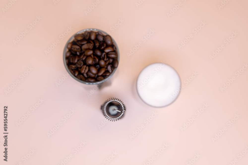 Milk foam maker with glass of milk on pink peach background.