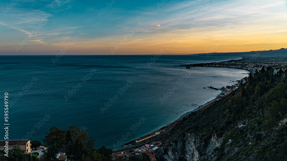 Panorama of the beach of Taormina, Sicily. Exciting sunset oversicilian sea seen from the terrace of the city, on the southern slopes of the Peloritani mountains, ionian coast, near Etna volcano.
