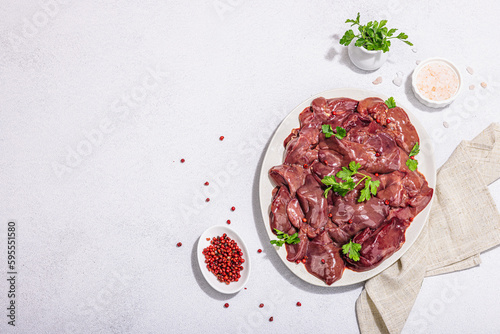 Raw chicken liver on stone background. Fresh ingredients ready for cooking, parsley, red pepper