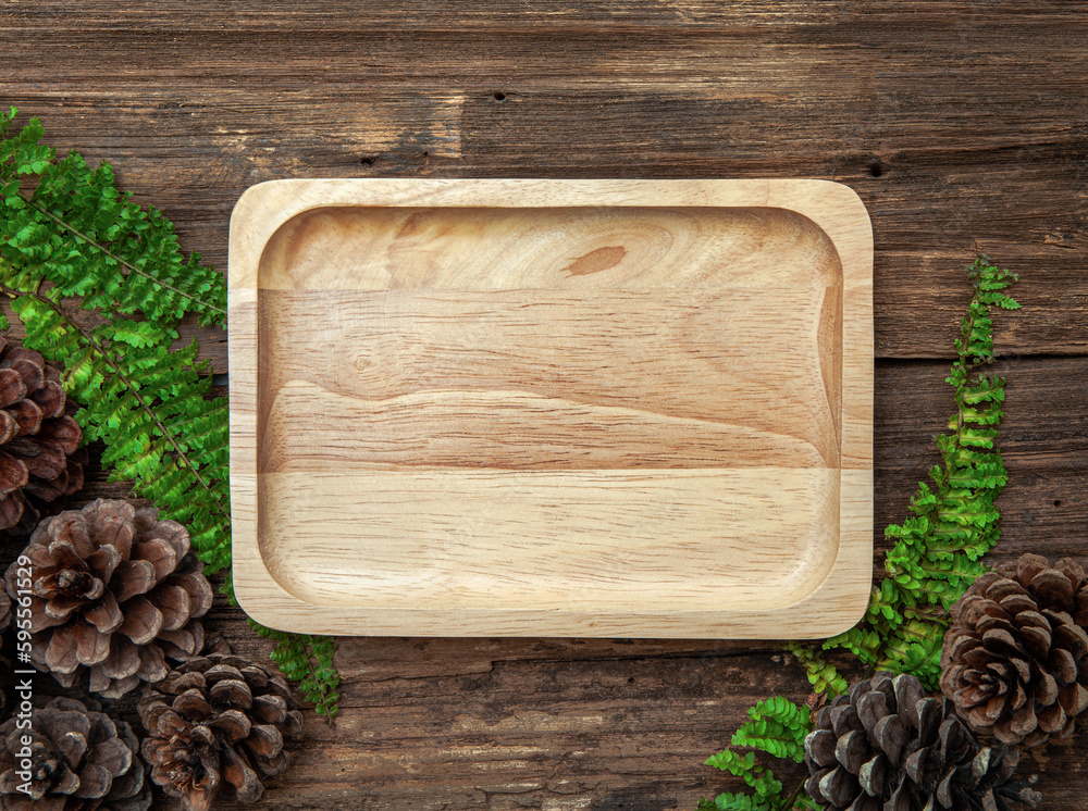 Wooden plate on wood texture background with leaves and pine cones. Top view of vintage brown wooden surface. Brown rustic wood for backdrop. Wooden plate on wood texture background with leaves and pine cones. Top view of vintage brown wooden surface. Brown rustic wood for backdrop.